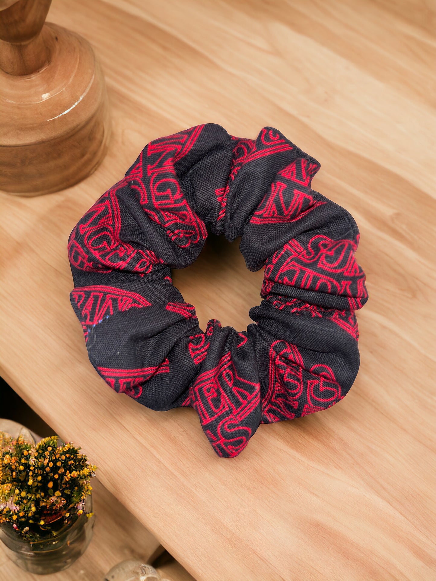Black scrunchie with red patterns on a wooden surface