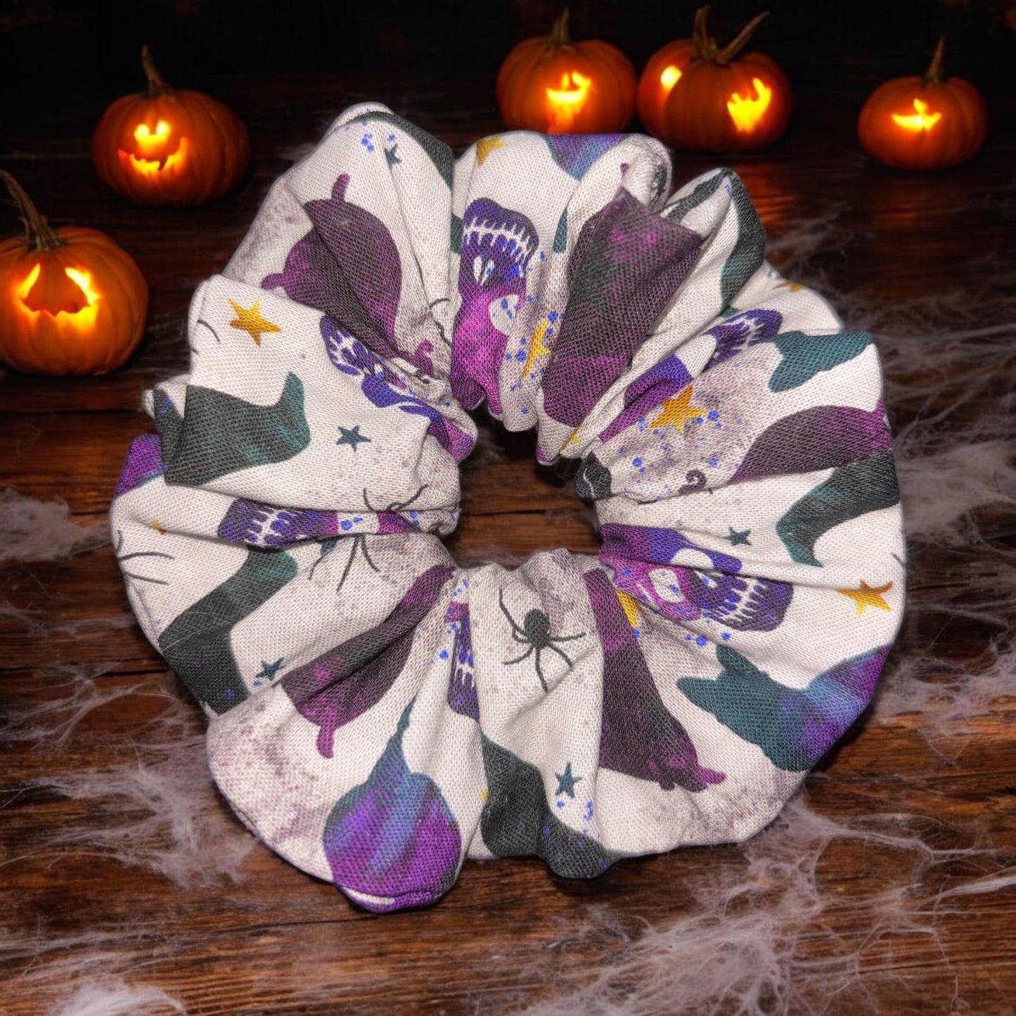 Halloween-themed  crows and cats scrunchie with pumpkins in the background