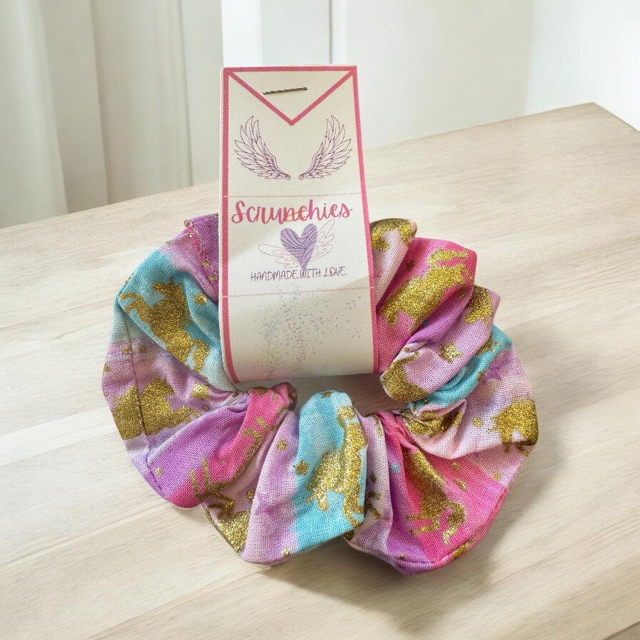 Colorful scrunchies with  unicorns on branded card on a wooden surface