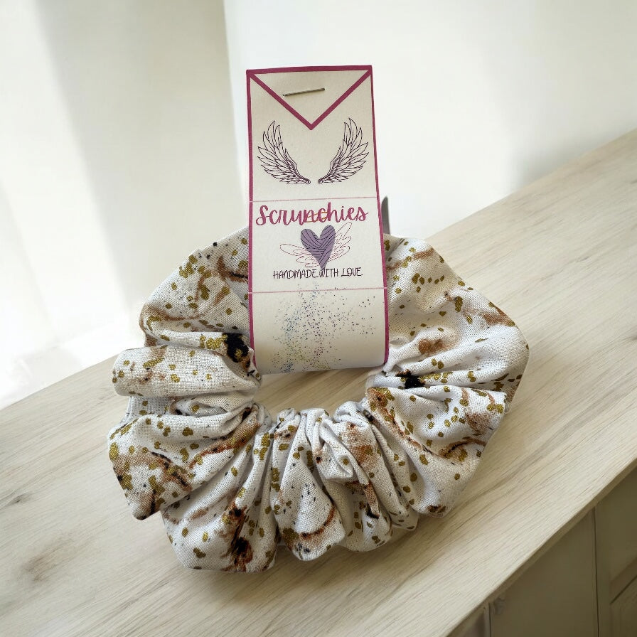 scrunchies on a wooden surface with a branded packaging label.