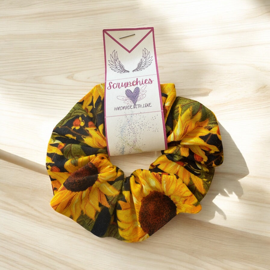 Sunflower patterned scrunchie with a branded card on a wooden surface