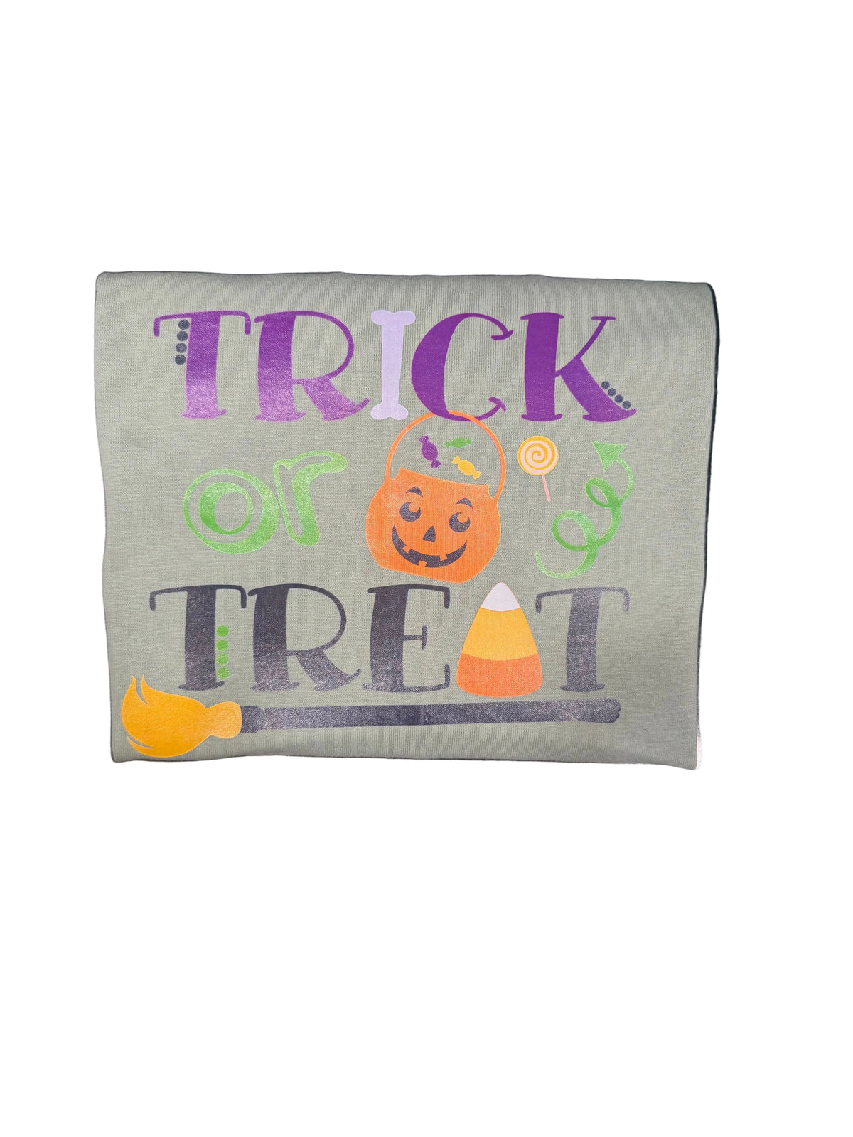A square sage green fabric patch with a colorful 'Trick or Treat' Halloween graphic, placed on a black marble surface.